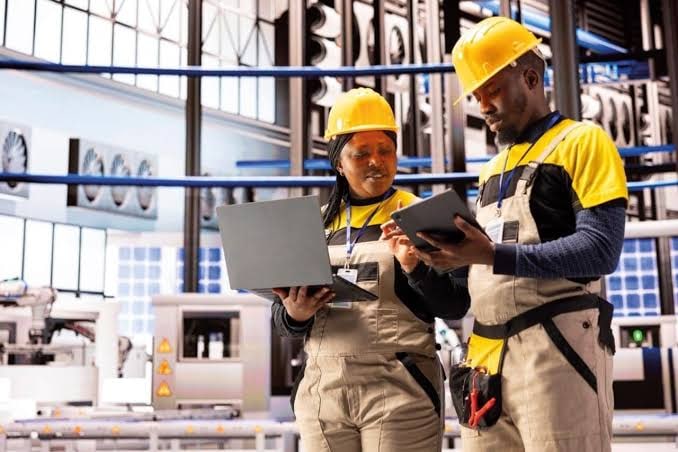 Two industrial automation engineers reviewing plant information on a laptop and tablet